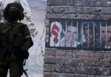 مقاتل من القسام يقف أمام صورة للجنديين الاسرائيليين المحتجزين في غزة