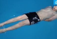 طفل يسبح مقيد القدمين واليدين