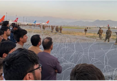 صورة لمواطنين أفغان ينتظرون دورهم في الصعود الى الطائرة مع وجود القوات الأمريكية لحراسة مطار كابول "AFP"
