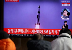 كوريون من كوريا الشمالية أثناء مشاهدتهم التجرية الصاروخية عبر شاشة عامة