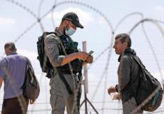 جندي إسرائيلي يدقق في الأوراق الشخصية لمواطن فلسطيني