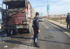 شرطي مرور يقف أمام شاحنة نقل احترقت على جسر وادي غزة