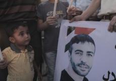 طفل يُمسك بشمعة أمام صورة الشهيد  ناصر أبو حميد