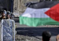 شاب يحمل علم فلسطين في مواجهة جنود الاحتلال