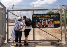مستوطنون يقفون بجانب صور الجنود الإسرائيليين الأسرى لدى كتائب القسام في غزة