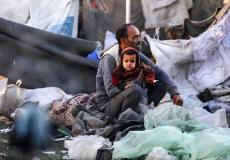 أي يحتضن طفله وسط الدمار في غزة - تعبيرية