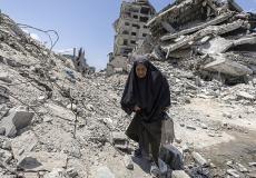 امرأة مسنة تمشي على أنقاض الدمار في غزة - تعبيرية