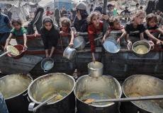 أطفال يحاولون الحصول على طعام من تكية خيرية في غزة - تعبيرية