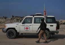 أحد عناصر القسام بجانب مركبة للصليب الأحمر