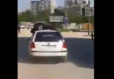 شرطى يعتلى سيارة مخالفة بغزة