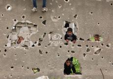 أطفال بغزة يقفون خلف جدار آيل للسقوط