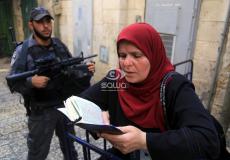 فلسطينية تقرأ القرآن وبجوارها جندي إسرائيلي بالقدس