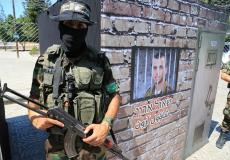 مقاتلين من كتائب القسام امام صورة للجندي الإسرائيلي المفقود في غزة شاؤول أرون