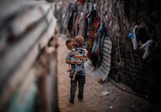 طفل يحمل شقيقه في أحد الاحياء الفقيرة في غزة