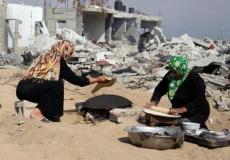 فلسطينيتان تعدان الخبز في العراء