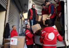 عمال بالهلال الأحمر السوري يفرغون حمولة إغاثية من شاحنة في دوما