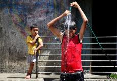 طفل يستحم بالمياه هربا من موجه الحر في غزة - APA