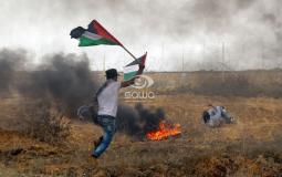 شاب يرفع العلم الفلسطيني خلال المواجهات مع قوات الاحتلال على حدود غزة اليوم