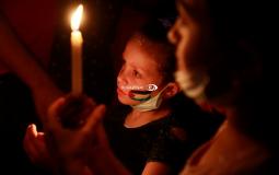 وقفة أطفال بالشموع على أنقاض منزل عائلتين في غزة