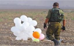 جندي اسرائيلي بجوار بالونات حارقة أطلقت من غزة