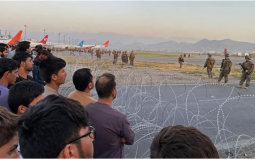 صورة لمواطنين أفغان ينتظرون دورهم في الصعود الى الطائرة مع وجود القوات الأمريكية لحراسة مطار كابول "AFP"