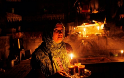 امرأة توقد شمعة بعد انقطاع التيار الكهربائي - تعبيرية