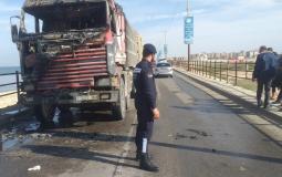 شرطي مرور يقف أمام شاحنة نقل احترقت على جسر وادي غزة