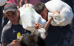 شابان يحملان مساعدات قرب رفح (رويترز)