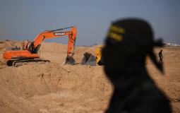 قاتل من «الجهاد الإسلامي» يراقب عمالاً مصريين يحفرون بآلية ثقيلة بحثاً عن جثث المختطفين في النصيرات شمال قطاع غزة الجمعة (أ.ب)