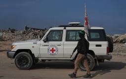 أحد عناصر القسام بجانب مركبة للصليب الأحمر