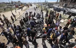 فلسطينيون يتجمَّعون حول سيارة مُدمَّرة بعد استهدافها بغارة إسرائيلية في شارع صلاح الدين جنوب مخيم البريج بقطاع غزة (أ.ف.ب)