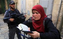 فلسطينية تقرأ القرآن وبجوارها جندي إسرائيلي بالقدس