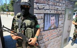 مقاتلين من كتائب القسام امام صورة للجندي الإسرائيلي المفقود في غزة شاؤول أرون