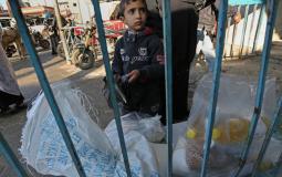 طفل يقف امام مركز توزيع اغذية تابع للاونروا بغزة