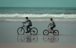 طفلان يركبان دراجة على شاطئ بحر غزة