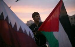 فلسطيني يرفع علمي فلسطين وقطر في غزة