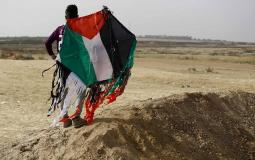 أحد المتظاهرين الفلسطينيين يمسك طائرة ورقية حارقة على حدود غزة