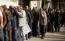 مواطنون مستفيدون من شيكات الشؤون الاجتماعية يصطفون أمام بنك فلسطين