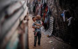 طفل يحمل شقيقه في أحد الاحياء الفقيرة في غزة