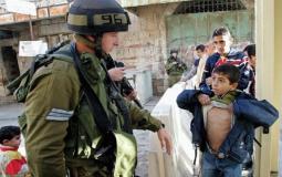 جندي إسرائيلي يفتش طفل فلسطيني