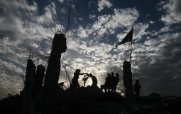 فلسطينيون من غزة يقفون على مبنى مدمر