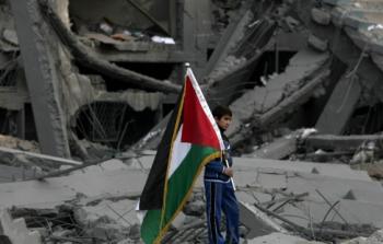 طفل يحمل علم فلسطين فوق أطلال منزله