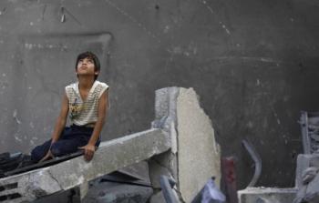 طفل يجلس على أنقاض منزله المدمر بغزة