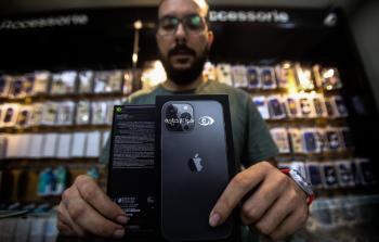 موظف من قسم التكنولوجيا في شركة سيتي فون يعرض جهاز أيفون 13 داخل معرض الشركة في مدينة غزة