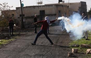 متظاهر فلسطيني يرشق جنود الاحتلال بقنبلة غاز