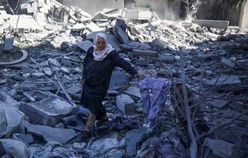 مسنة فلسطينية تقف على أنقاض منزل مدمر في قطاع غزة