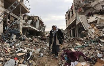 مسنة تمشي على أنقاض الدمار في غزة - تعبيرية