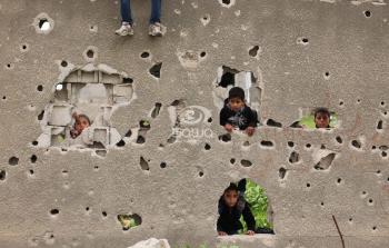 أطفال بغزة يقفون خلف جدار آيل للسقوط
