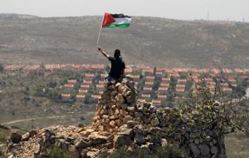 فلسطيني يرفع علم بلاده بالقرب من تجمعات استيطانية