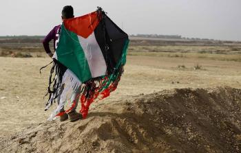 أحد المتظاهرين الفلسطينيين يمسك طائرة ورقية حارقة على حدود غزة